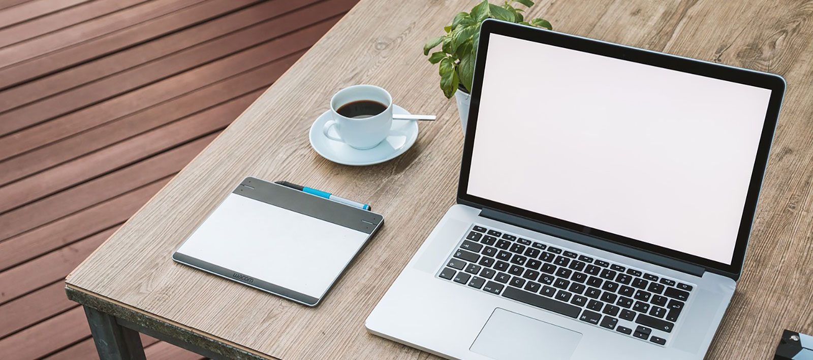 Laptop op een bureau met een kopje koffie en een plantje